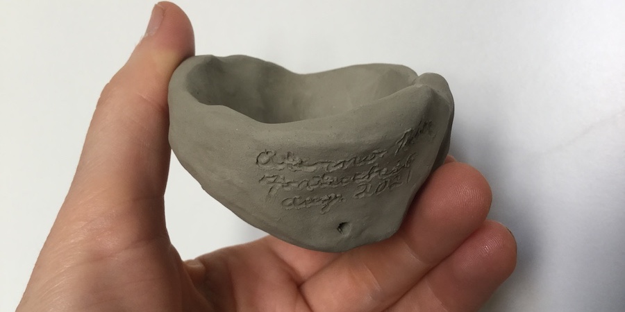 Clay clepsydra held in the hand of the artist