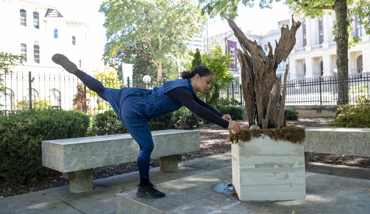 Performer beside one of the monuments in Emergence